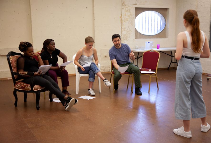 Monologue workshop with 4 people seated watching and one performing